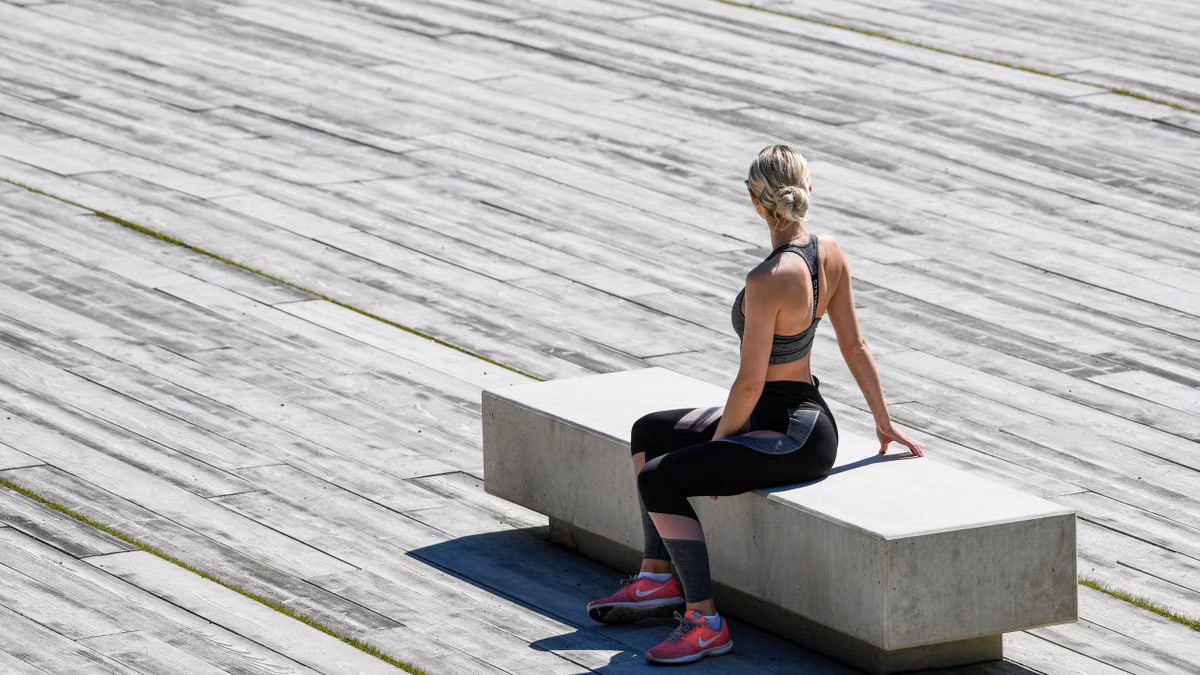 A young woman meditating outdoors on a concrete bench, embracing tranquility and mindfulness.